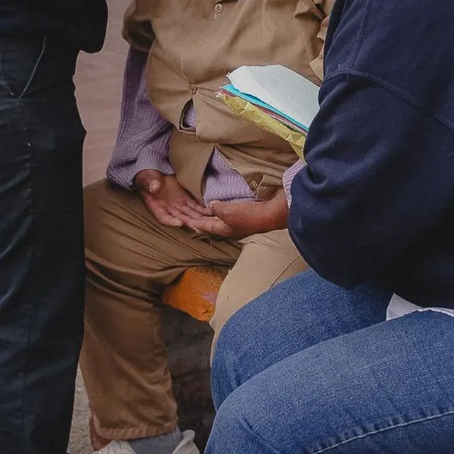 Detalle de manos que sostienen hojas y una Biblia durante un encuentro.