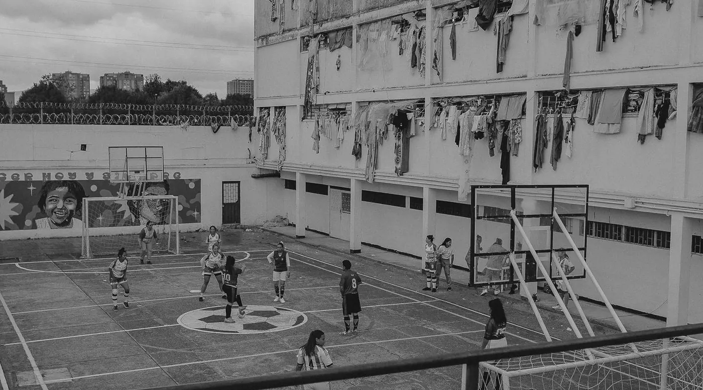 Mujeres juegan fútbol en el patio de la cárcel El Buen Pastor, rodeado de pabellones.