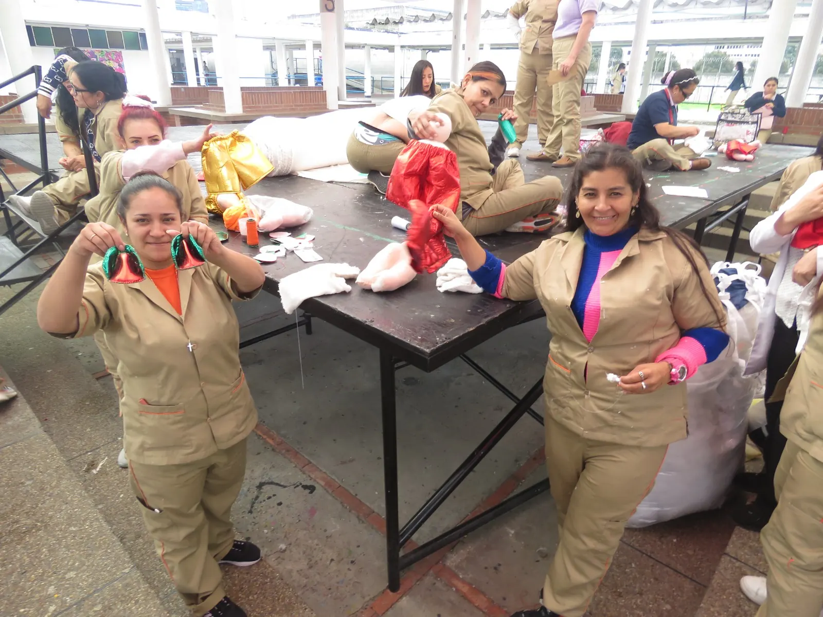 Mujeres en un taller productivo muestran con alegría las piezas que están elaborando.